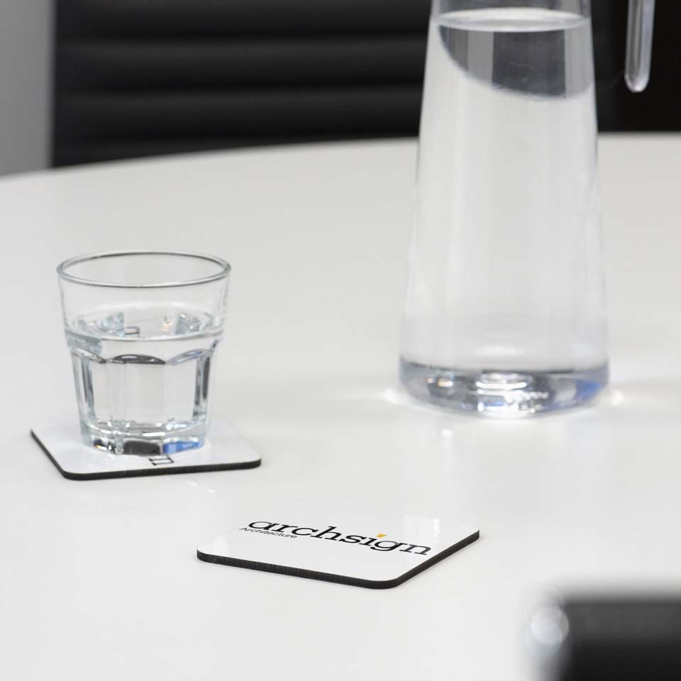 Branded coaster on table with glass and jug