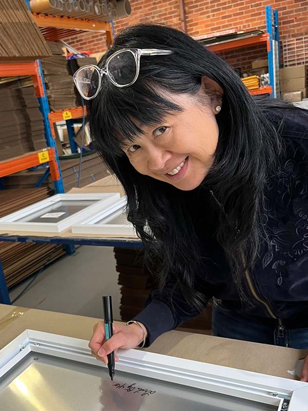close up of Linda signing metal artwork