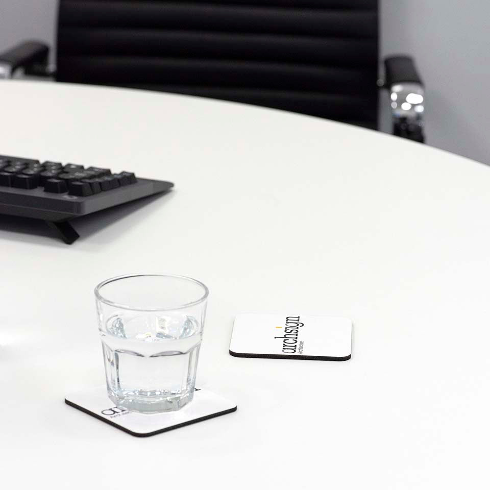 Branded coaster on table with glass and keyboard