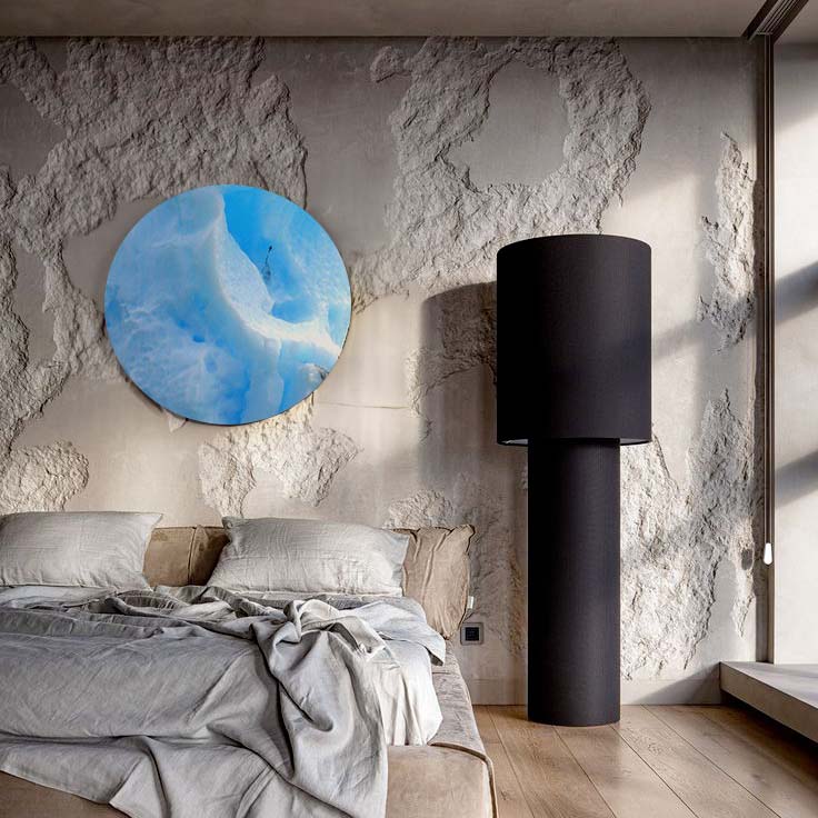 Circular metal print on textured wall in modern bedroom